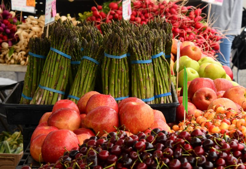 Asparagus, apples, and cherries on display at a farmers market stand