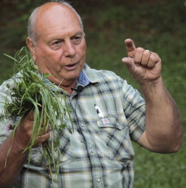 Danny Boyer holding a clump of grass and explaining about pasture  health